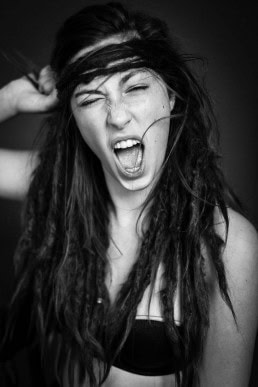 Black and white portrait of young woman with dreadlocks screaming