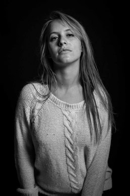 Black and white headshot portrait of a dirty-blond hair woman wearing a loose sweater
