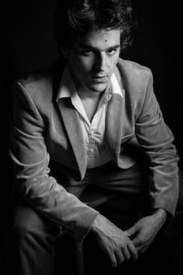 Black and white portrait of dark-haired young man wearing a suit without a tie