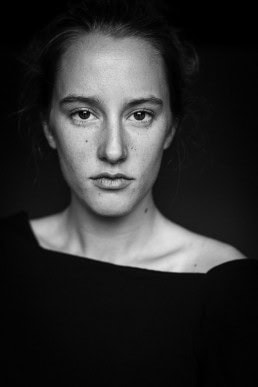Black and white headshot portrait of a woman looking straight at the camera