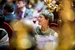 Closeup of a woman in the audience smiling during a Gala dinner event in Brussels