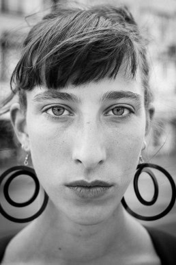 Black and white closeup portrait of a woman with big earings from France taken in Brussels