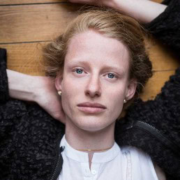 Portrait of a ginger woman with blue eyes laying over parquet