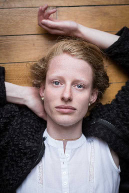 Portrait of a ginger woman with blue eyes laying over parquet