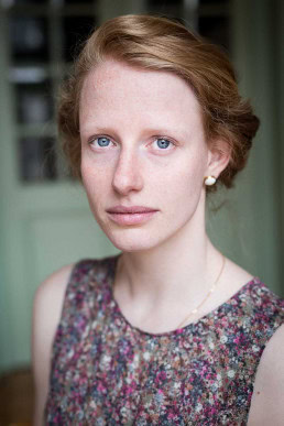 Headshot portrait of a ginger woman with blue eyes