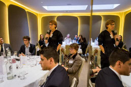 A speaker talks standing next to a round table during a meeting conference in Brussels