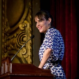 A woman speaker smiles while addressing the audience during a Gala dinner event in Brussels