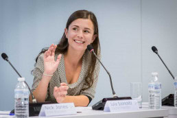 A woman speaker smiles and salutes in a conference for JA Europe in Brussels