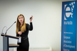 A speaker moving her left hand up while explaining her slides to the audience
