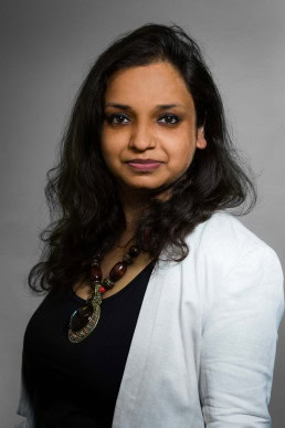 Corporate headshot portrait of a woman wearing a white jacket against a gray background