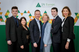 A group of people pose in front of a banner for a JA Europe event in Brussels