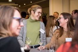 Two women speak and laugh during the Stellenbosch University cocktail at the South African Embassy, Brussels