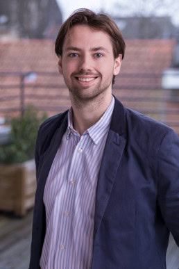 Corporate portrait of a man smiling wearing a blue jacket