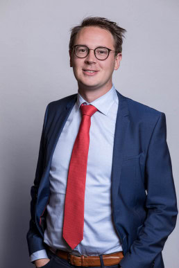 Corporate portrait of a man wearing a blue suit with a red tie