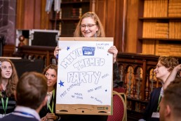 A girl smiles and holds a white board during the Skills for the Future event in Brussels