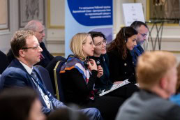 Two members of the audience speaking with each other during the 9th meeting of the WGECC in Brussels