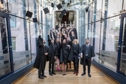 Students from the Institute for European Studies throwing their hats to the air after getting their diploma