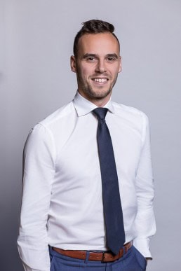 Corporate portrait of a man smiling wearing a white shirt and tie for Berquin Notarissen in Brussels	