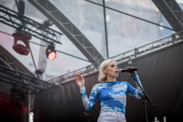 A blond woman sings and performs on stage in front of the EU Parliament in Brussels