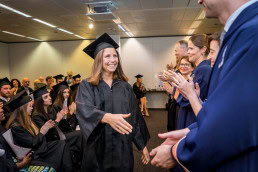 A student girl smiles and is about to shake hands before receiving her diploma from the Institute for European Studies
