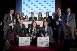 A group of people poses presenting their award on stage after getting a prize