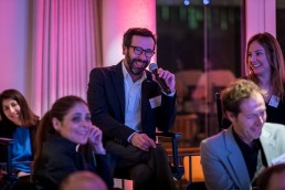 A man from the audience smiles while posing a question during the Netflix Belgium Walking Dinner