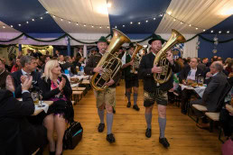 Two man carrying music instruments walk inside the tent of the 2019 Oktoberfest Brussels
