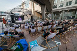 People sitting outside the European Parliament while watching an EU debate during the 2019 Youth Week