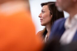 A woman in an audience listening to a speaker