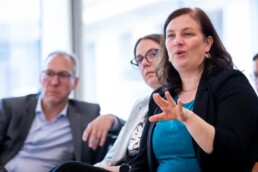A woman asking a question while gesturing with her hand