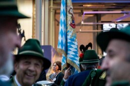 A typical Bavarian flag with people in the foreground dressed in a typical Bavarian costume