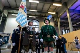Men dressed in typical bavarian customs with a flag