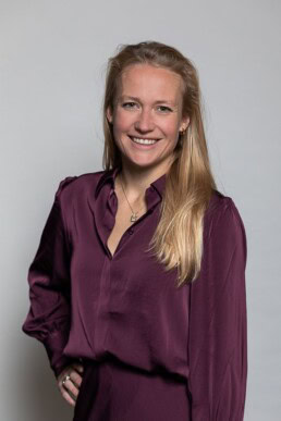 Portrait of a woman smiling with long blonde hair wearing a purple blouse for Berquin Notarissen in Brussels
