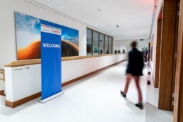 A man walking towards a hallway where there is a sign stating 