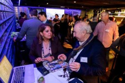 Two people having a conversation on the foreground while the background is full of people also speaking with each other during the NYC Tourism Convention in Brussels