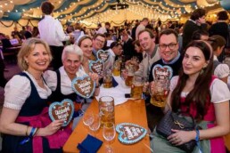 A group of people holding the Bavarian cookie and smiling at the camera during the Brussels Oktoberfest 2025