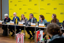 A group of people sitting at a conference table, including Peter Hauk