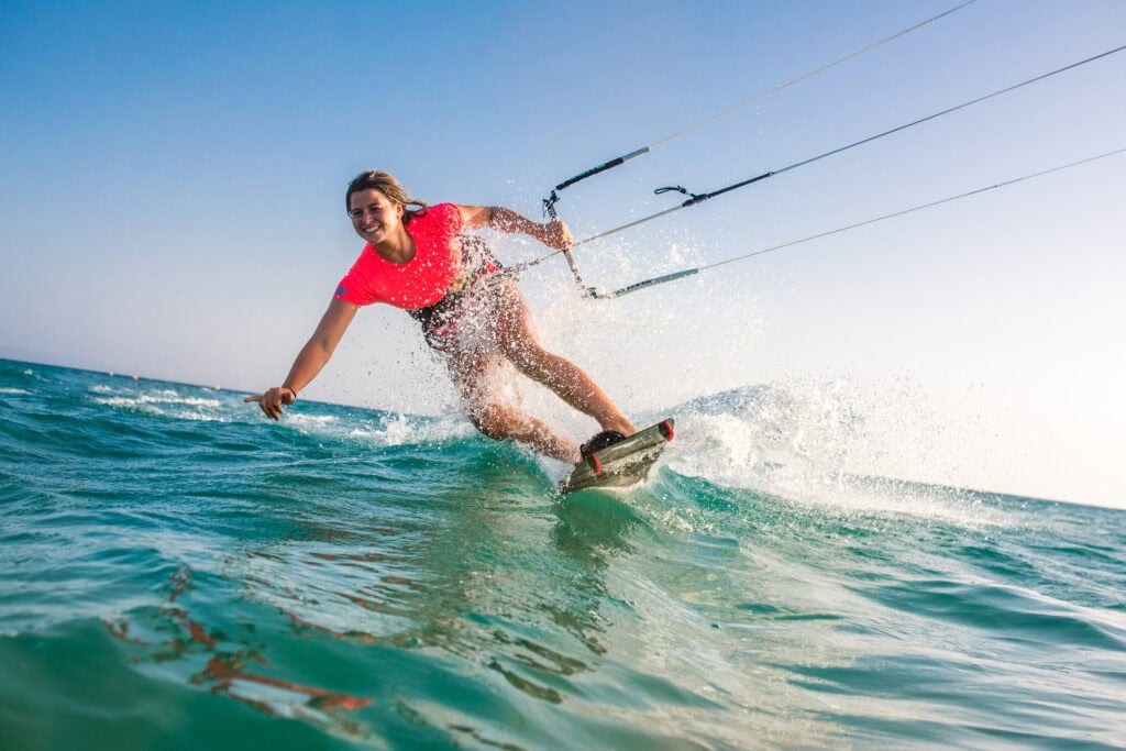 Woman doing kitesurfing on sea and smiling.