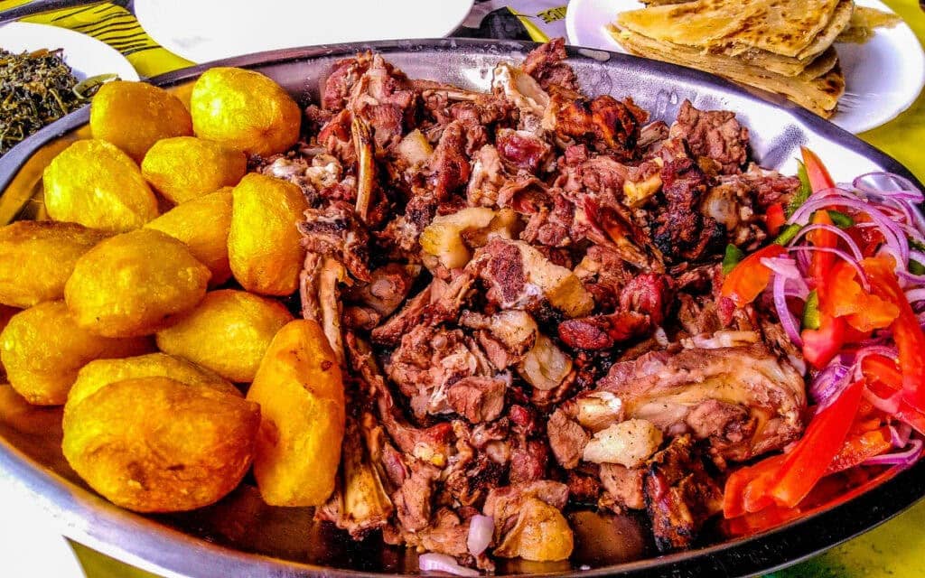 Sharing platter of a traditional Kenyan dish, Nyama choma and accompaniments of kachumbari salad | Photo: Jennifer Watson via Getty