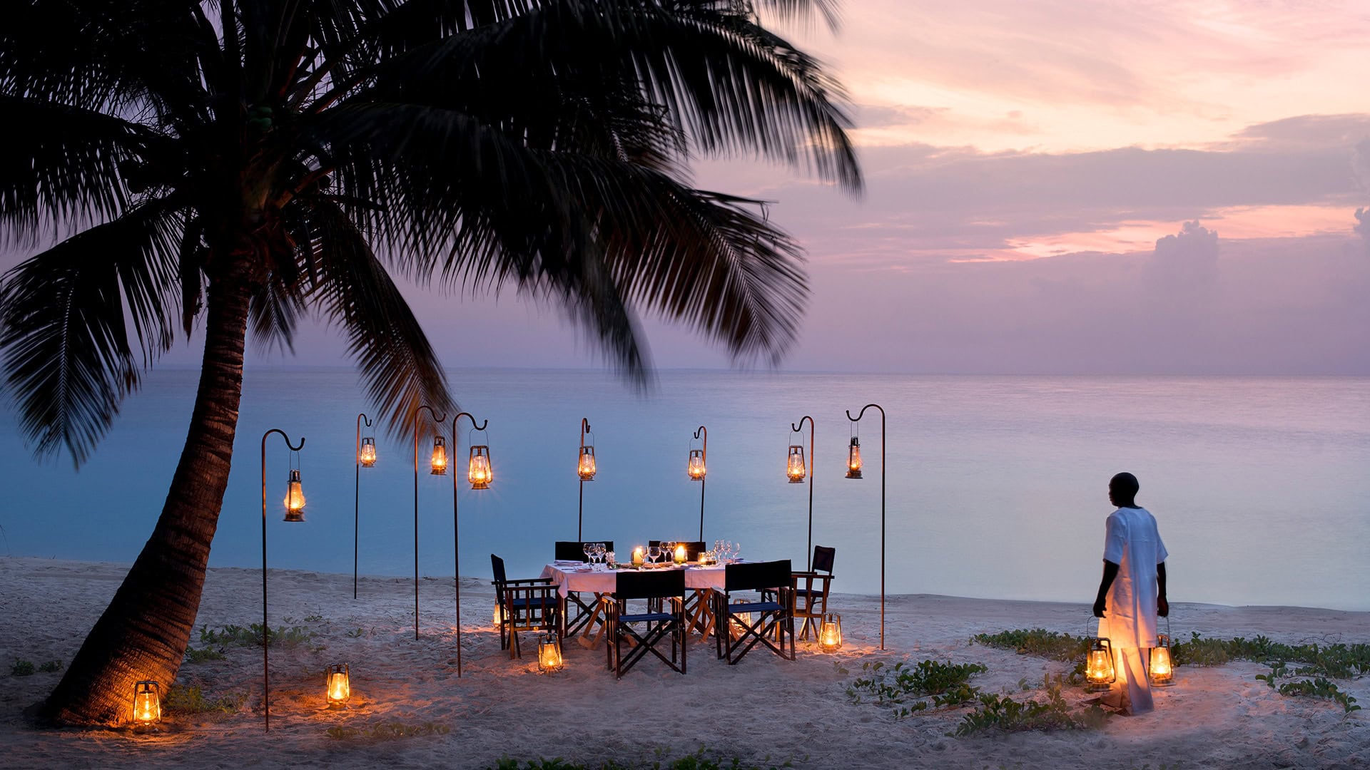 Dining on the beaches of Benguerra at sunset under a palm tree on an African Island beach holiday