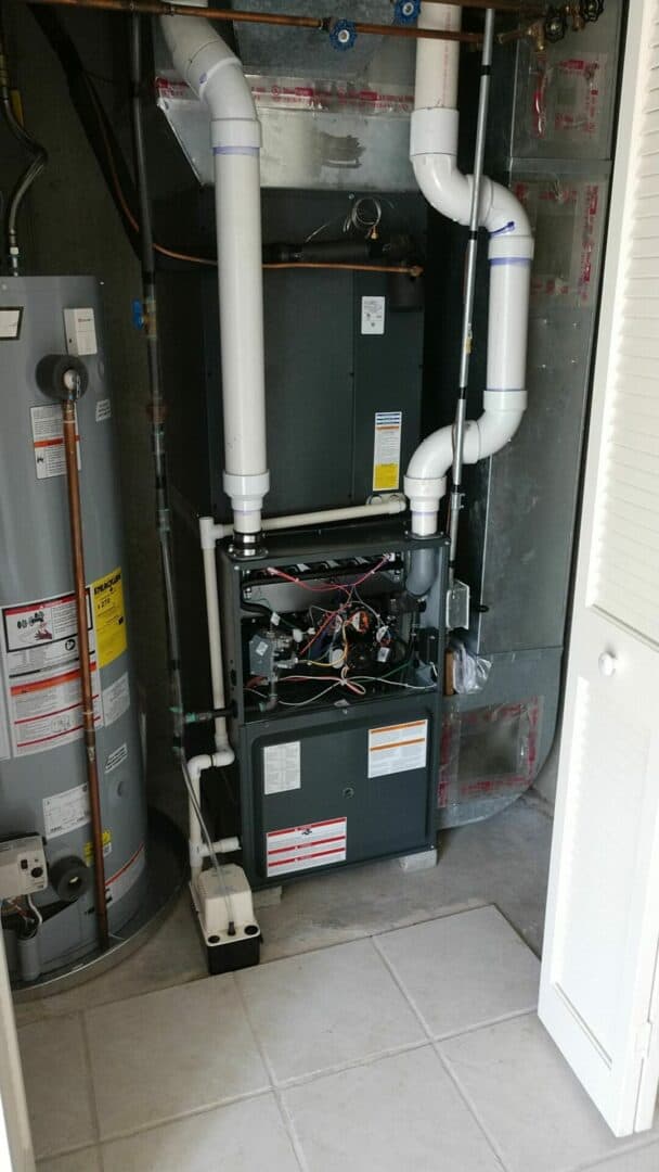 Indoor HVAC unit with piping and control panel in a utility room.