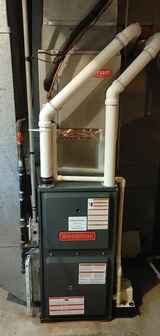 HVAC furnace system with white PVC pipes and Goodman unit in a utility room.