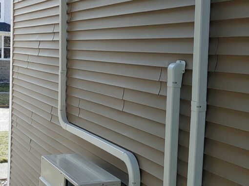 External HVAC unit with electrical wiring and conduit on beige siding.