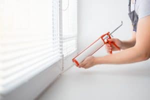 Contractor applying sealant around a home window frame