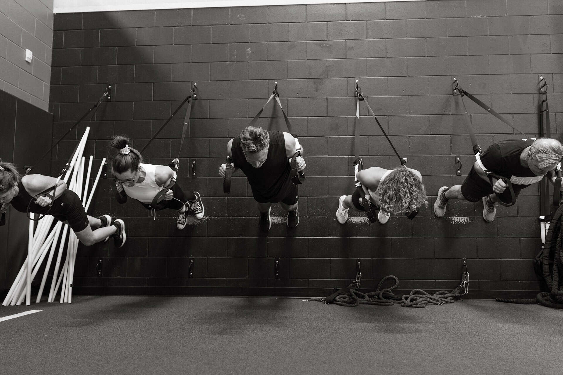 People doing suspension training exercises in a fitness studio.