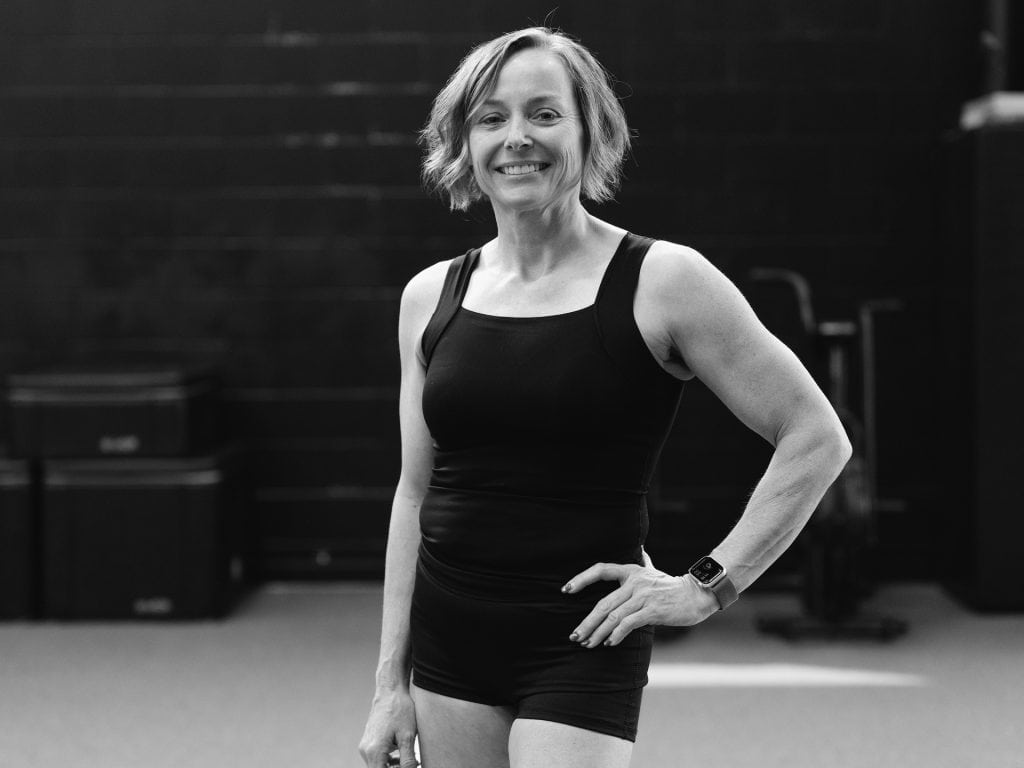 Female Pilates and yoga instructor smiling in studio, black and white photo.