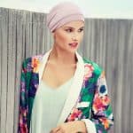Woman wearing a pink turban and colorful floral blazer outdoors.