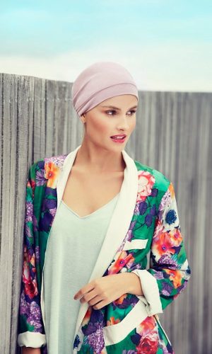 Woman wearing a pink turban and colorful floral blazer outdoors.