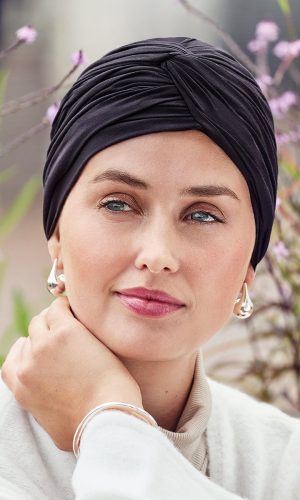 Elegant black turban headwrap worn by a woman outdoors.