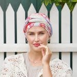 Woman wearing a printed turban with a white picket fence background.